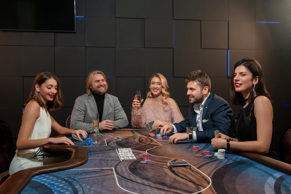 Friendly people drinking alcohol and playing poker at gaming table in casino